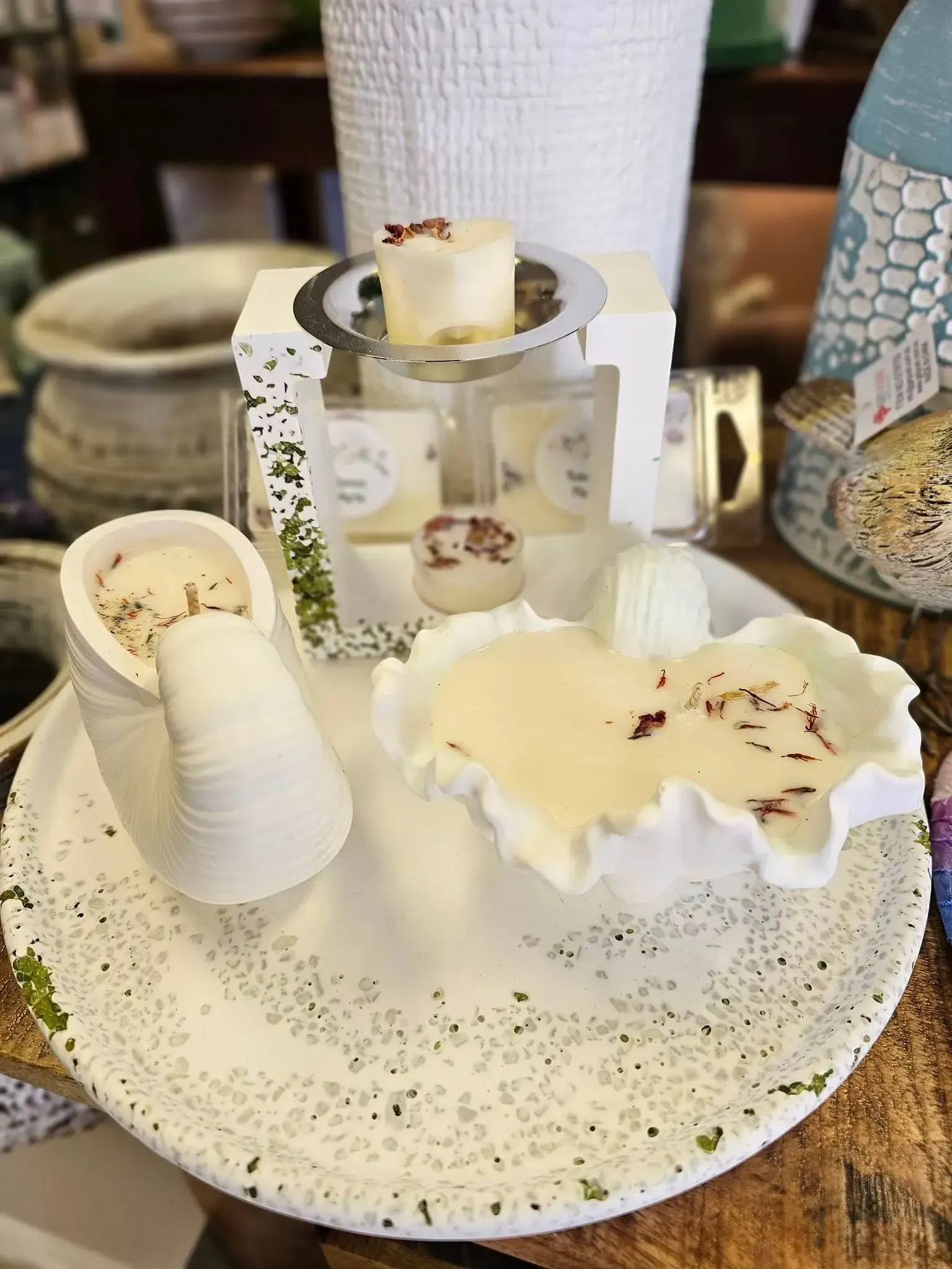 Decorative white ceramic candle set on a speckled plate with small mushrooms and moss accents