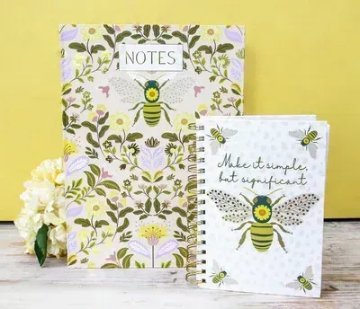Floral bee-themed notebooks on a yellow background, one labeled “NOTES”