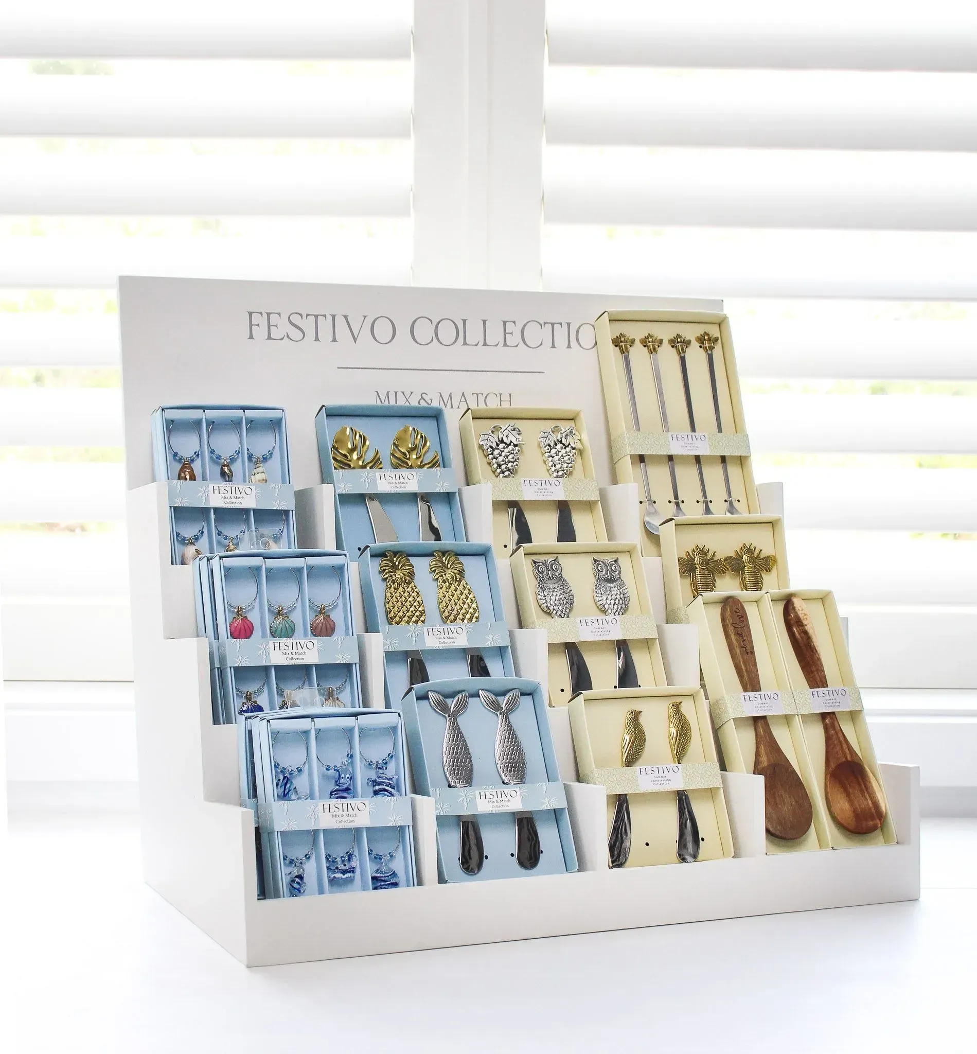 Assorted earrings displayed on a white stand in blue, gold, and cream packaging