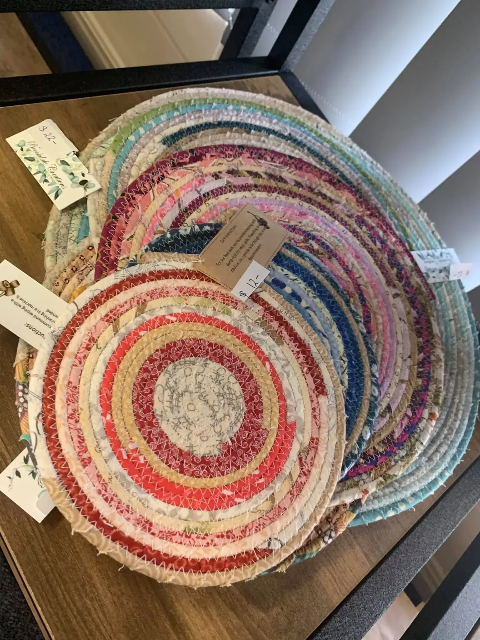 Colorful woven round placemats stacked on a table, with red, pink, blue, and natural stripes.