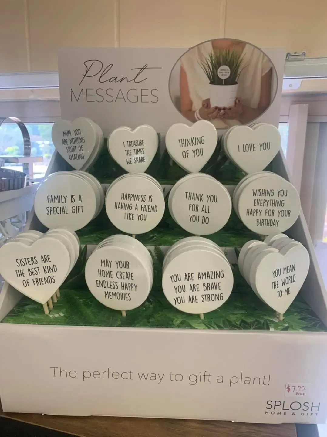 Plant Messages display with heart-shaped signs on a stand in a bright shop window.
