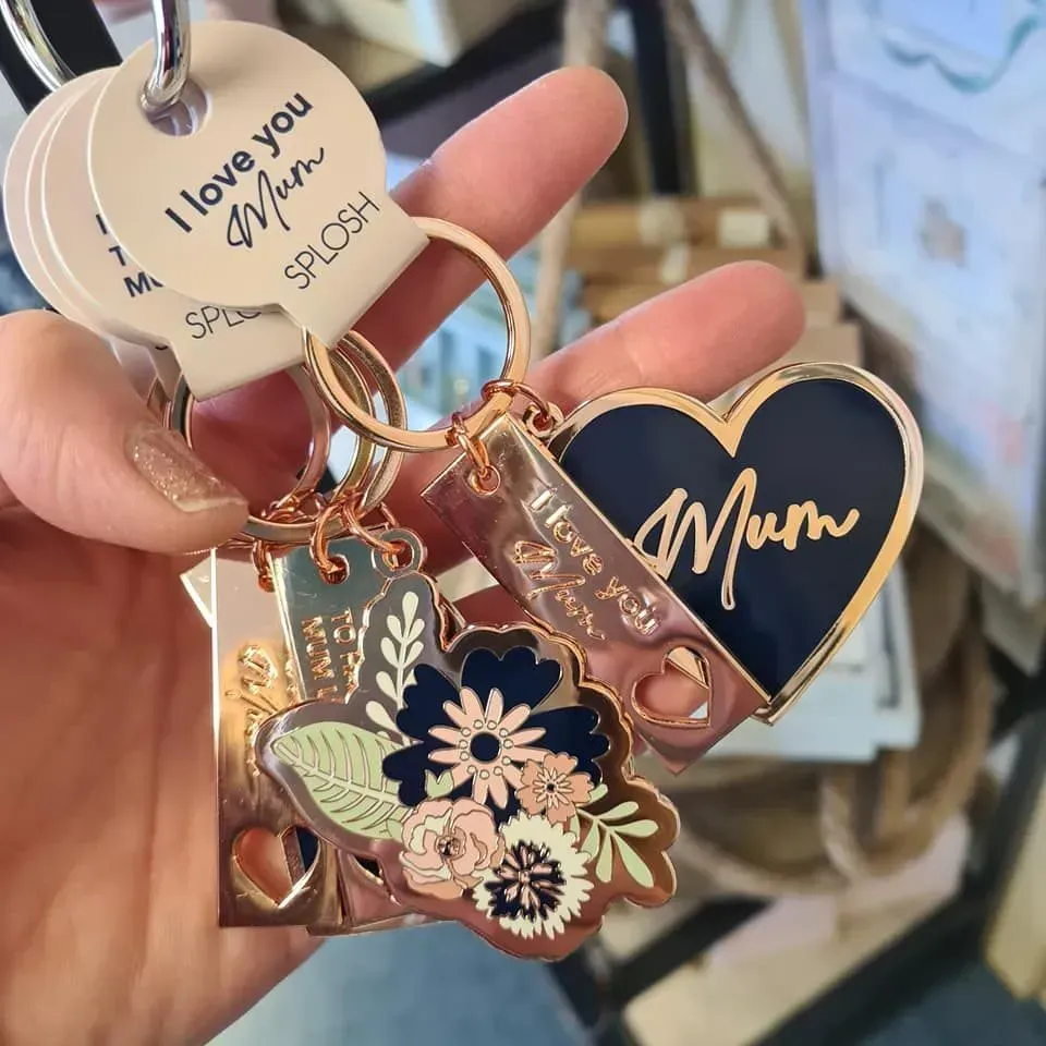 Hand holding floral keychain and black heart keychain engraved “Mum” and “I love you”