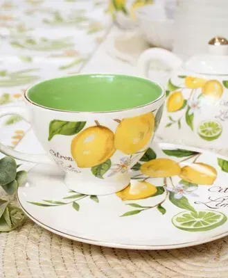 Lemon-patterned teacup and saucer with green interiors on a woven placemat