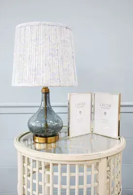 Lamp on a glass-topped side table with two white books against a light wall