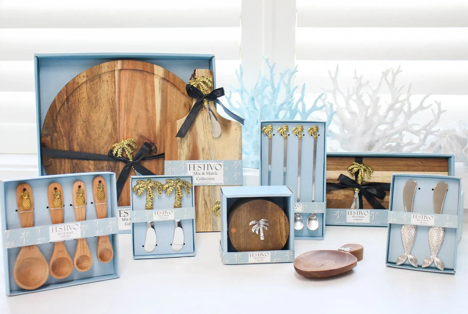 Blue gift boxes with wooden kitchen utensils, bows, and a round cutting board arranged on a white table.