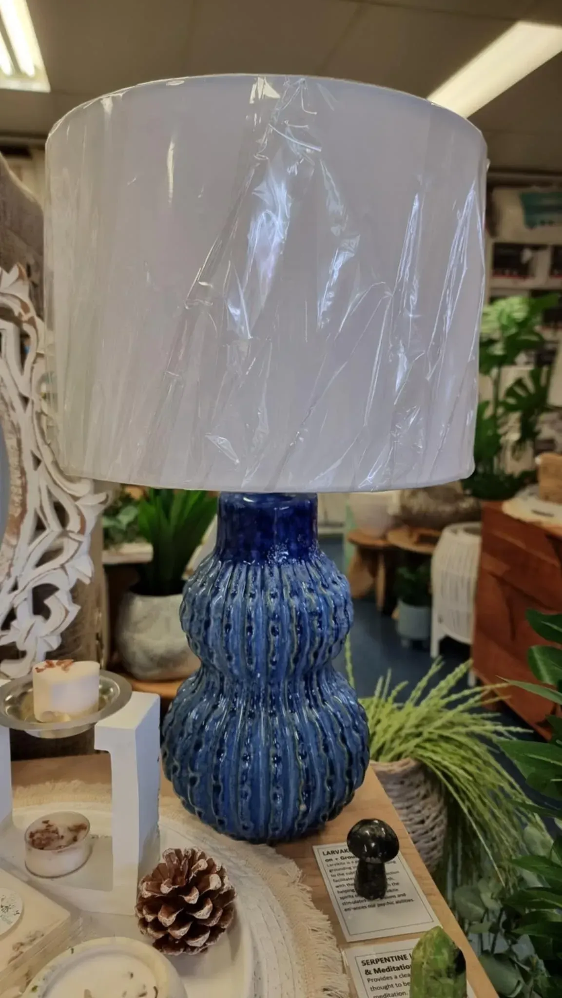 Blue textured table lamp with a white drum shade on a store display table
