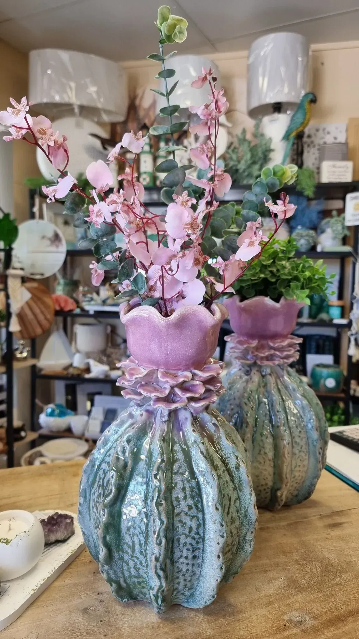 Two ornate floral sculptures with pink blossoms and blue-green bases in a craft studio