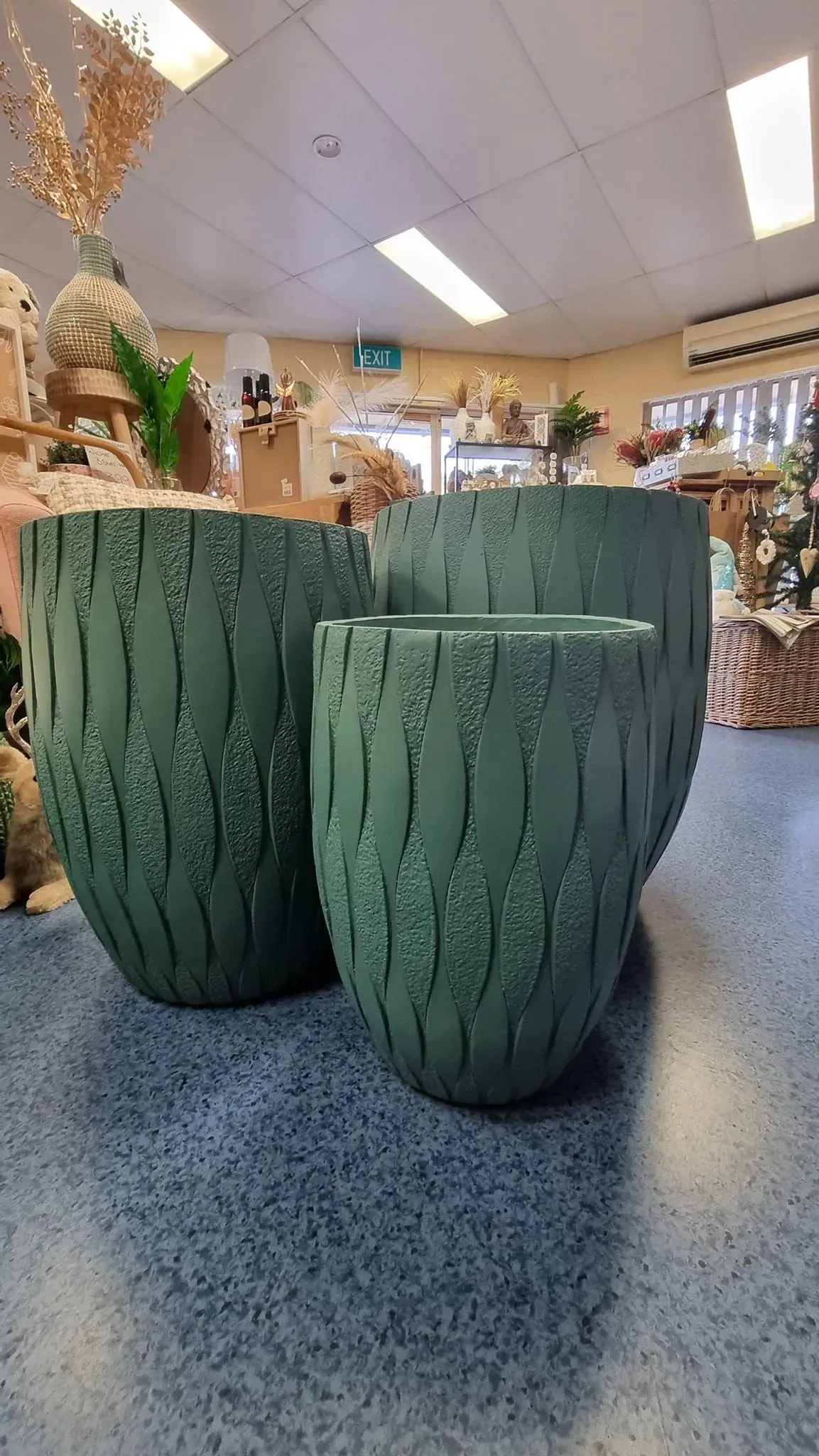 Two green ceramic planters on a tabletop in a store or café interior.