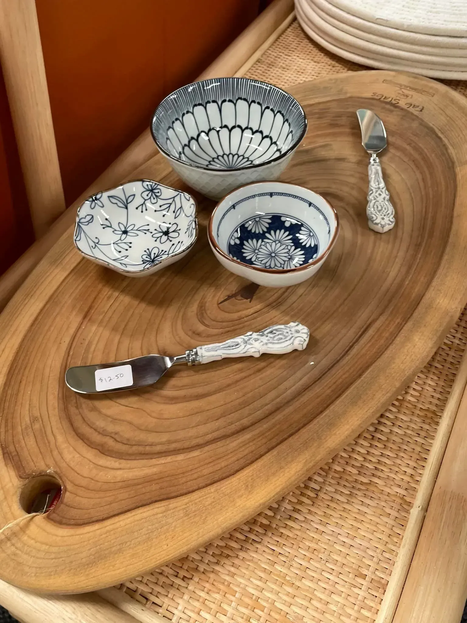 Small decorative ceramic bowls and serving utensils on a wooden tray.