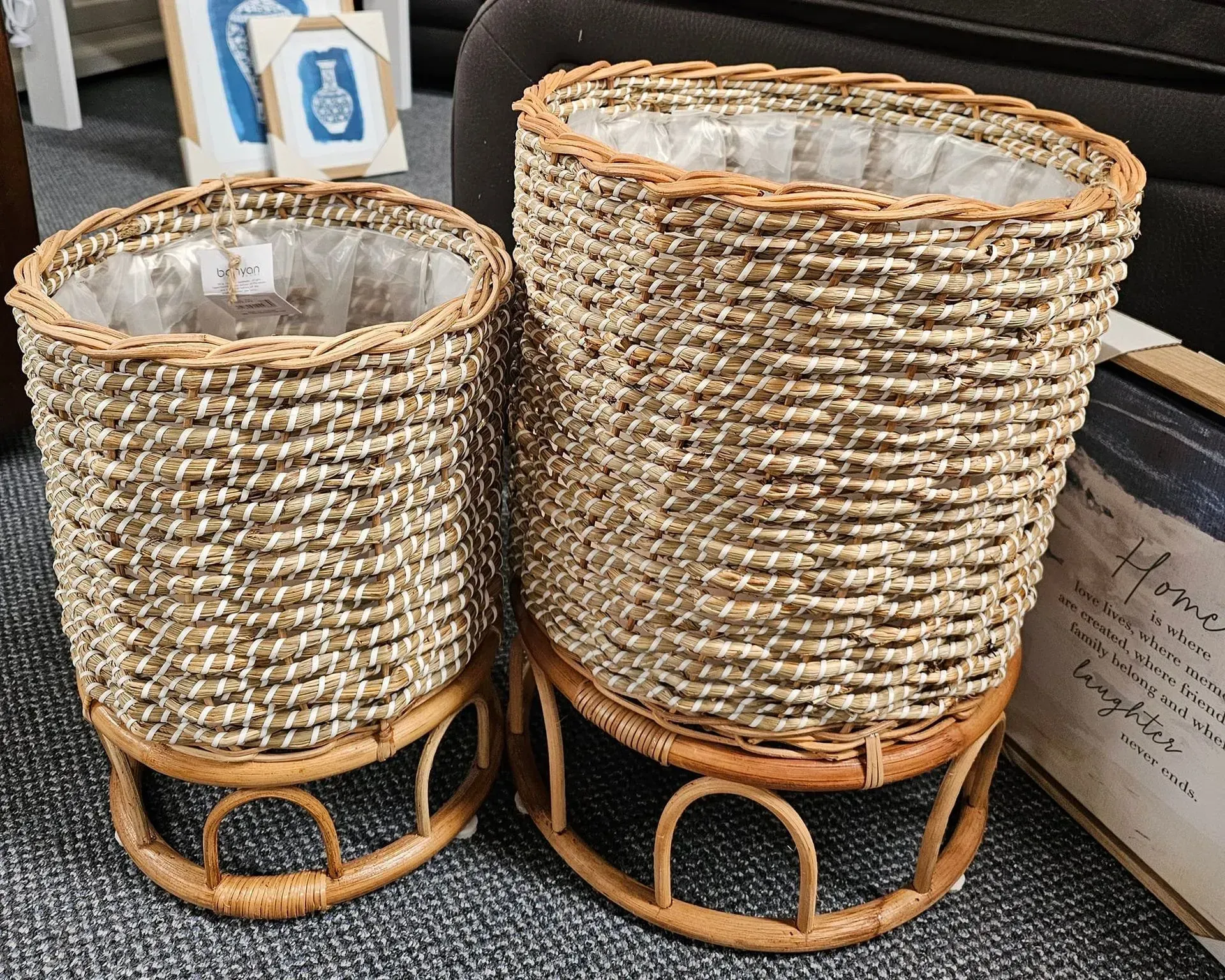 Two woven basket planters in tan wicker with metal frames on a gray surface