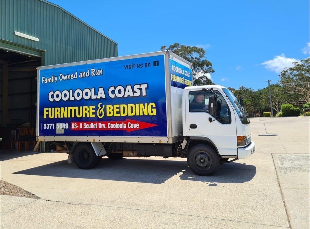 Blue Cooloola Coast Furniture & Bedding delivery truck parked outdoors on a sunny day