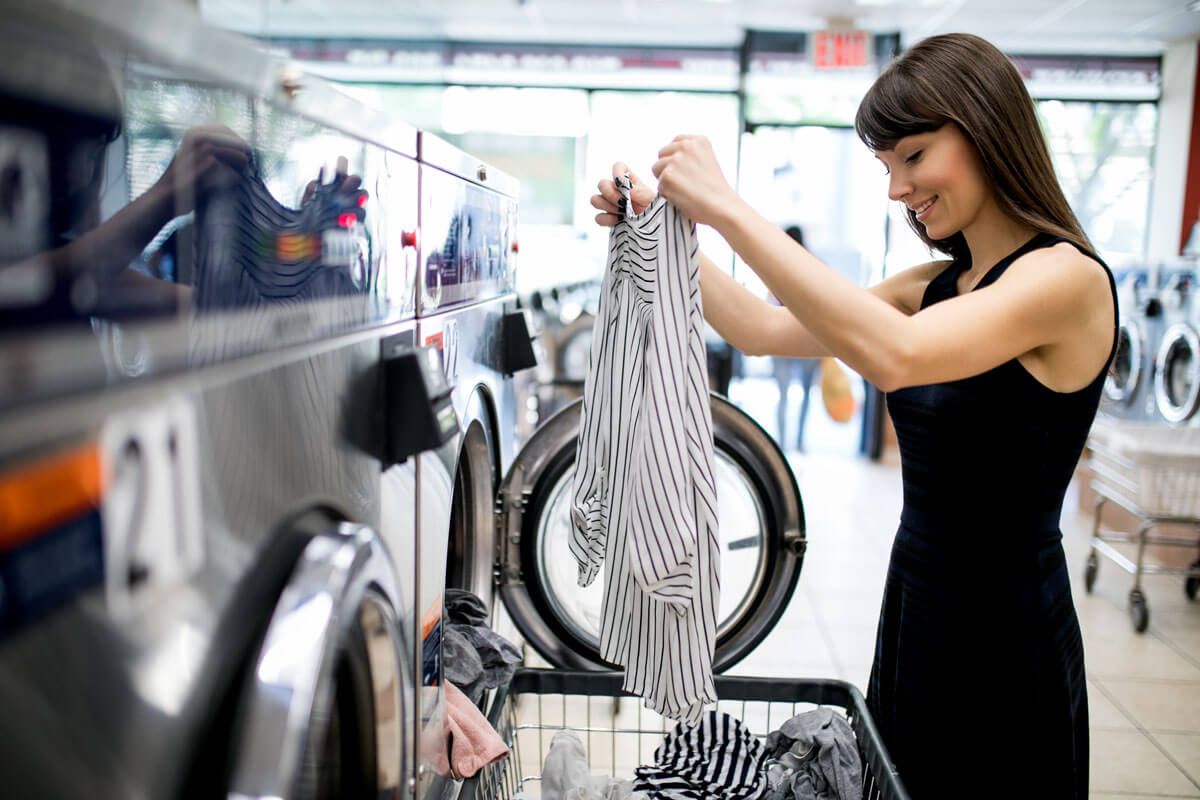 Woman loading laundry into a washing machine at a laundromat