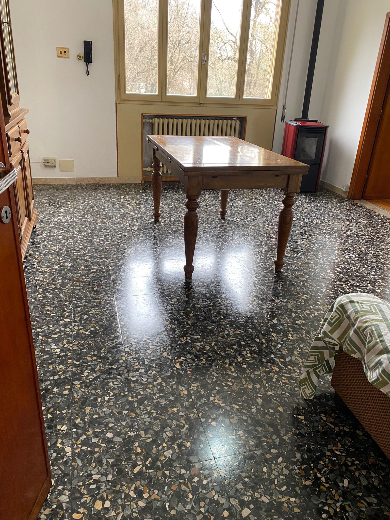 Stanza vuota con pavimento lucido bianco e nero, tavolino in legno, finestre e un divano sulla destra.
