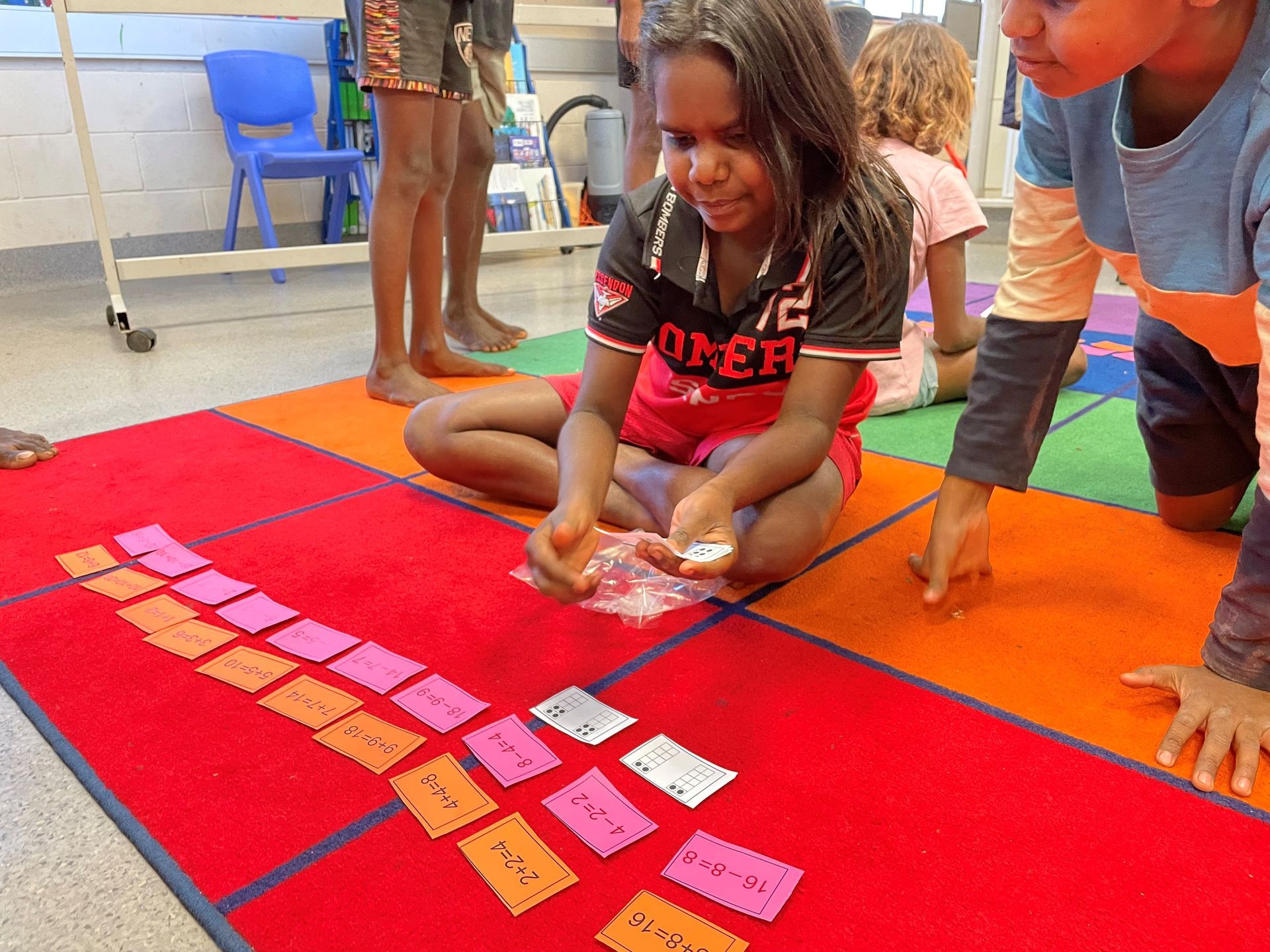 A girl is sitting on the floor playing a game with cards.