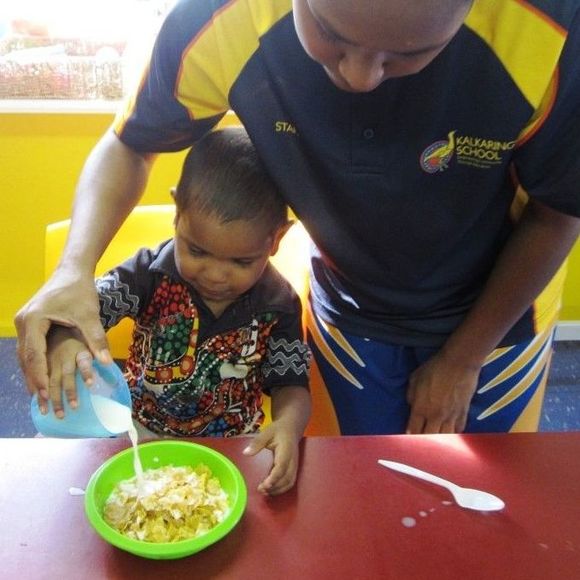 A man is pouring milk into a bowl of cereal