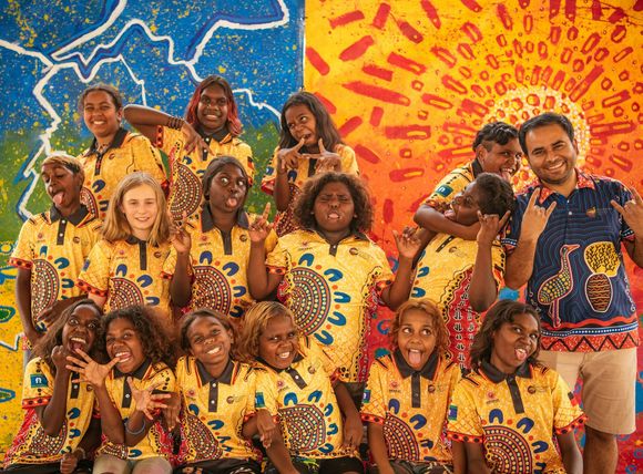 A group of people are posing for a picture in front of a colorful wall.