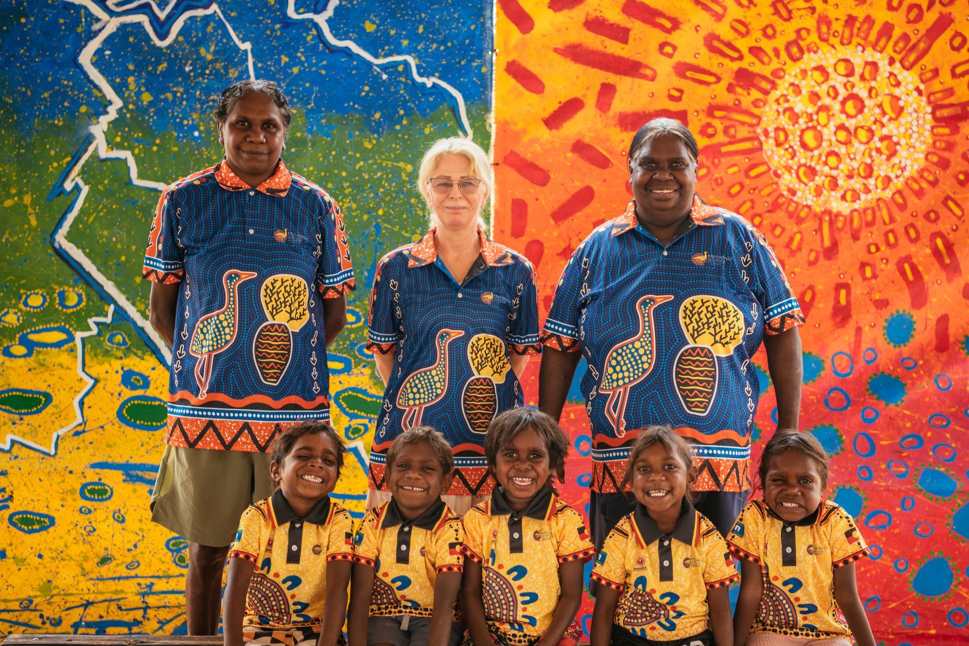 A group of people are posing for a picture in front of a colorful wall.