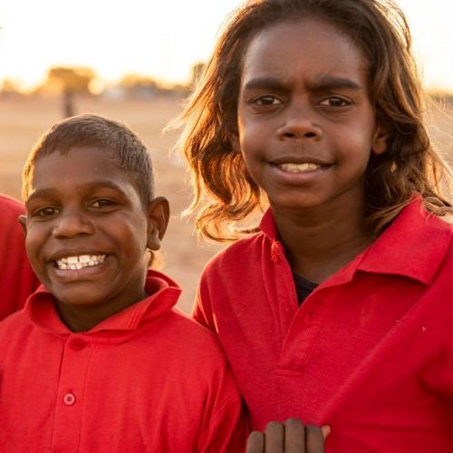 A boy and a girl in red shirts are posing for a picture
