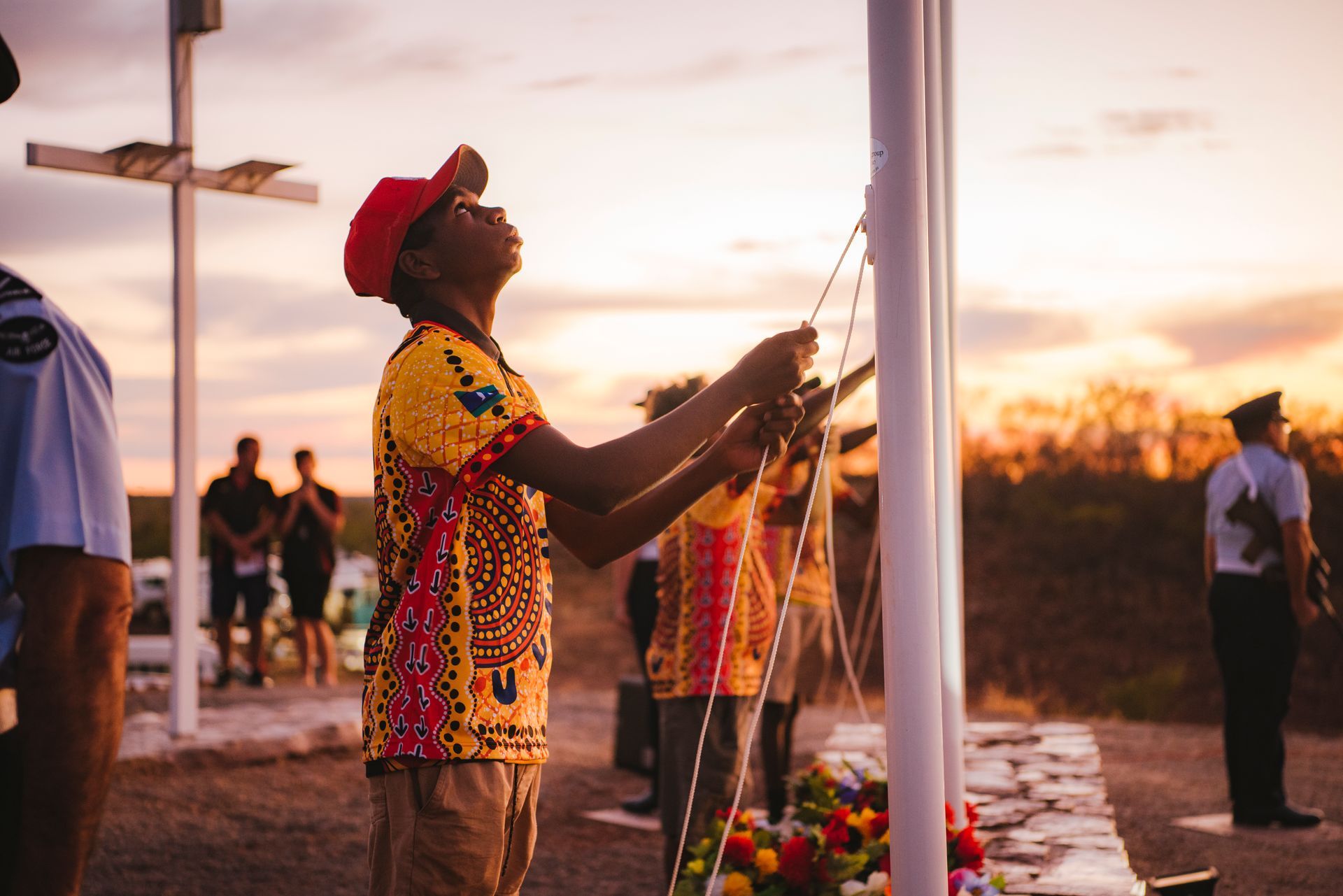 A man in a red hat is standing in front of a flag pole.