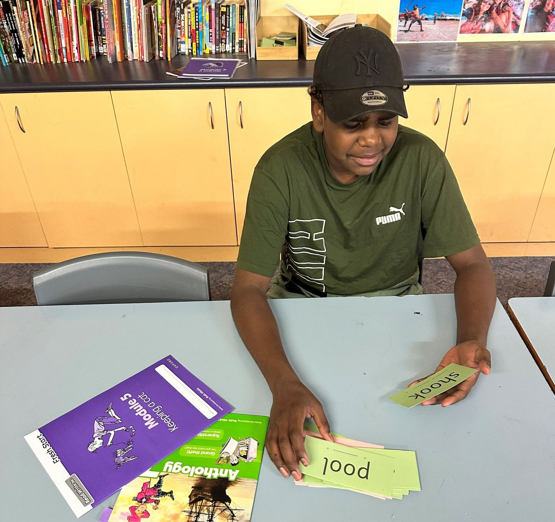A boy is sitting at a table with a book that says pool on it