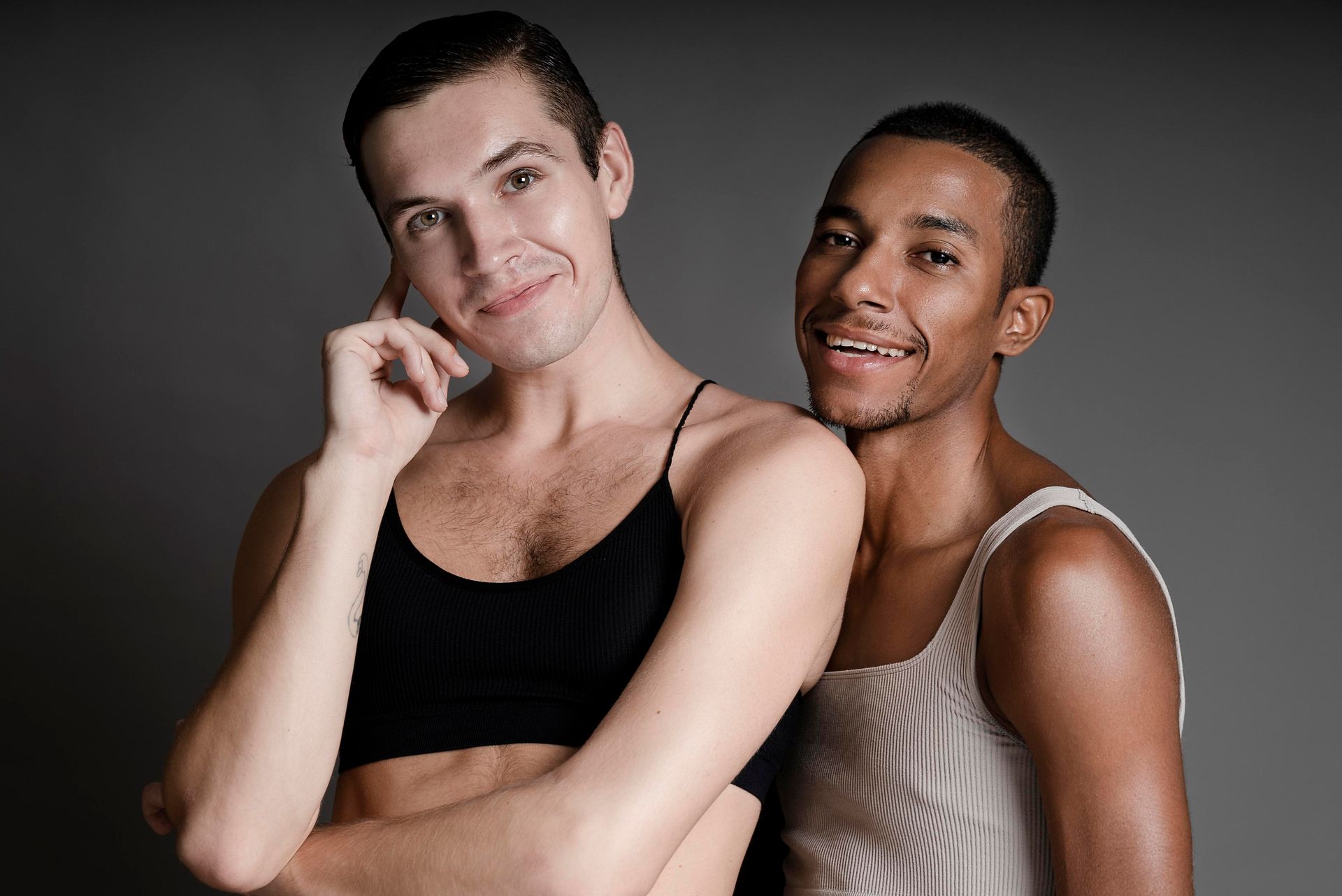 Two men are posing for a picture and one of them is wearing a bra.