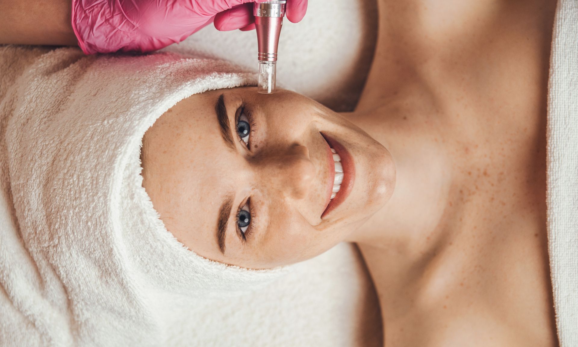 A woman with a towel wrapped around her head is getting a facial treatment.