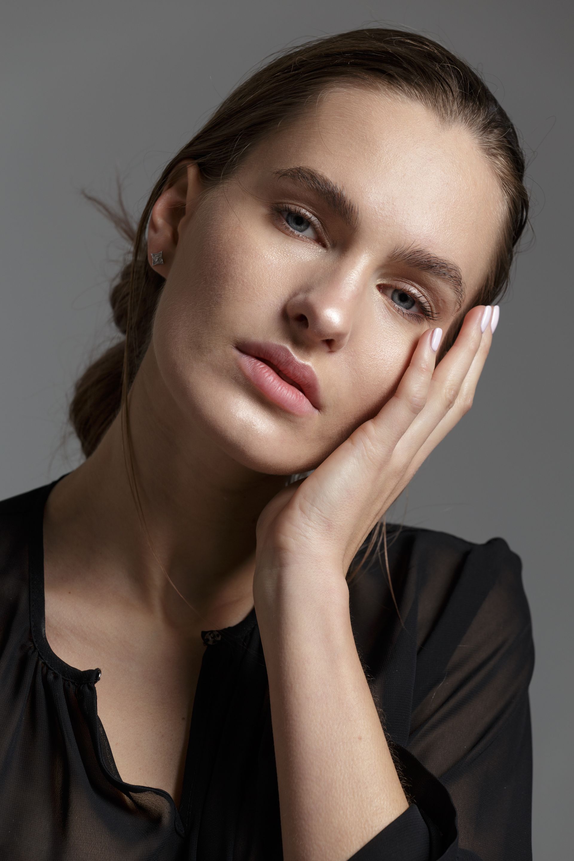 A close up of a woman 's face with her hand on her face.
