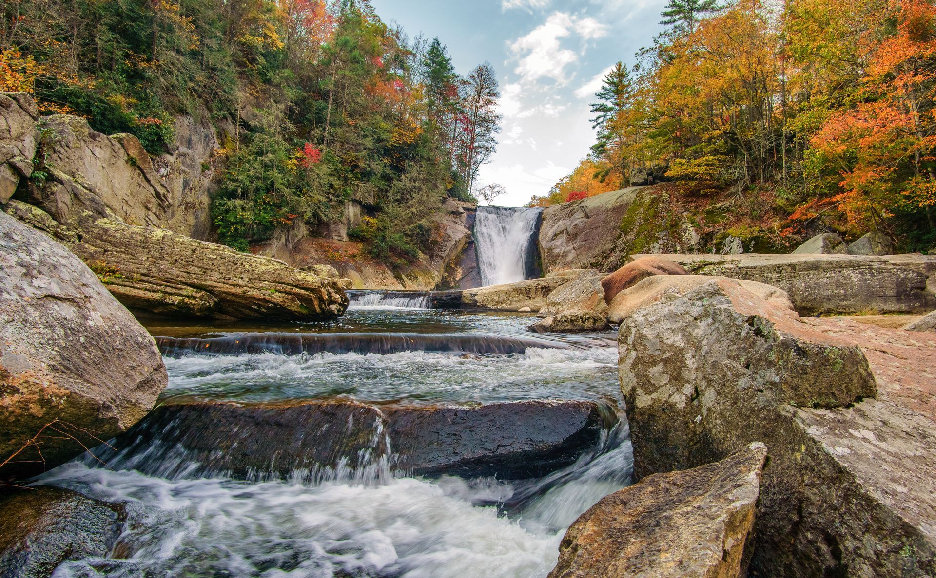 A waterfall is surrounded by rocks and trees in the middle of a forest.
