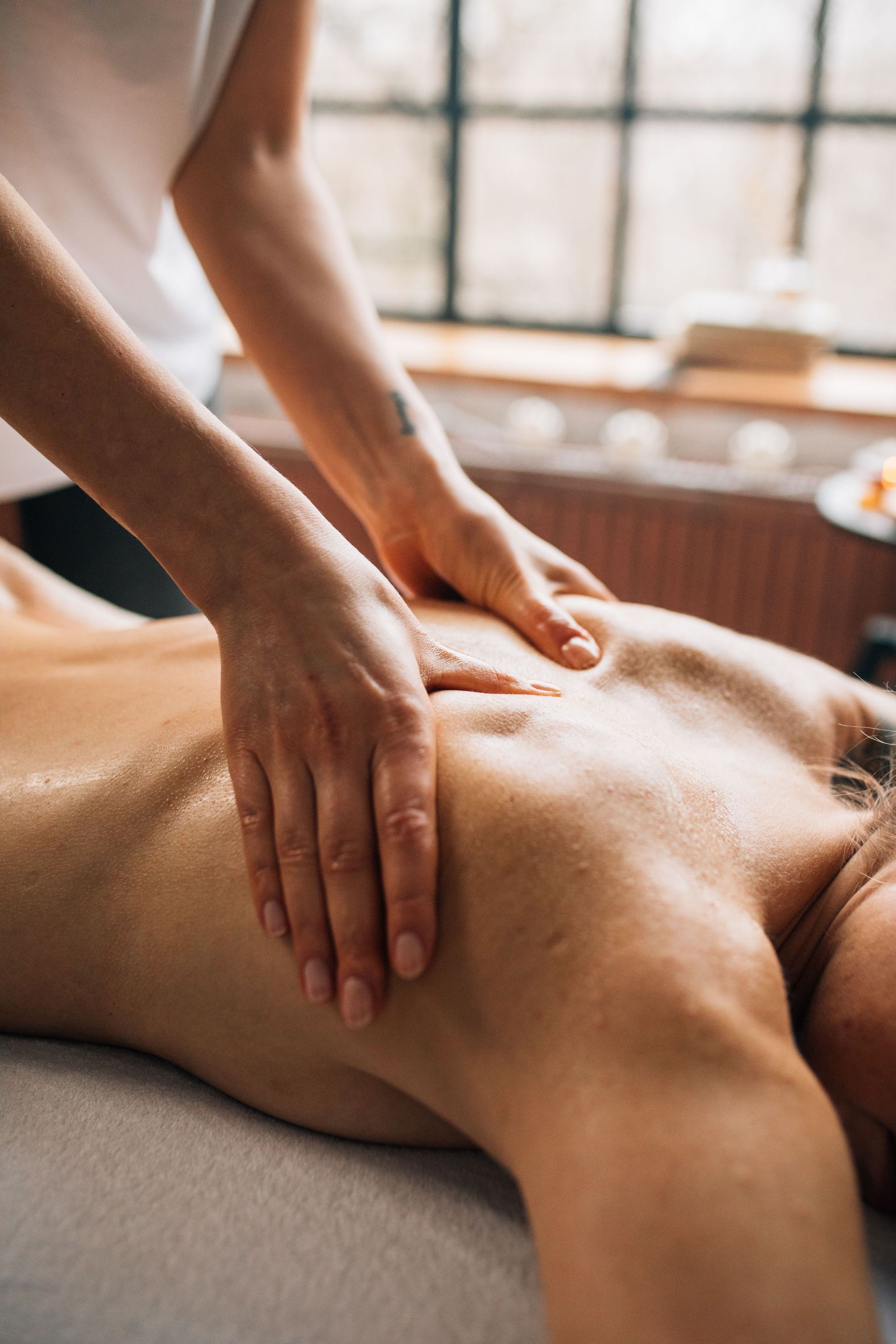 Hands giving a back massage on a person lying face down in a spa room