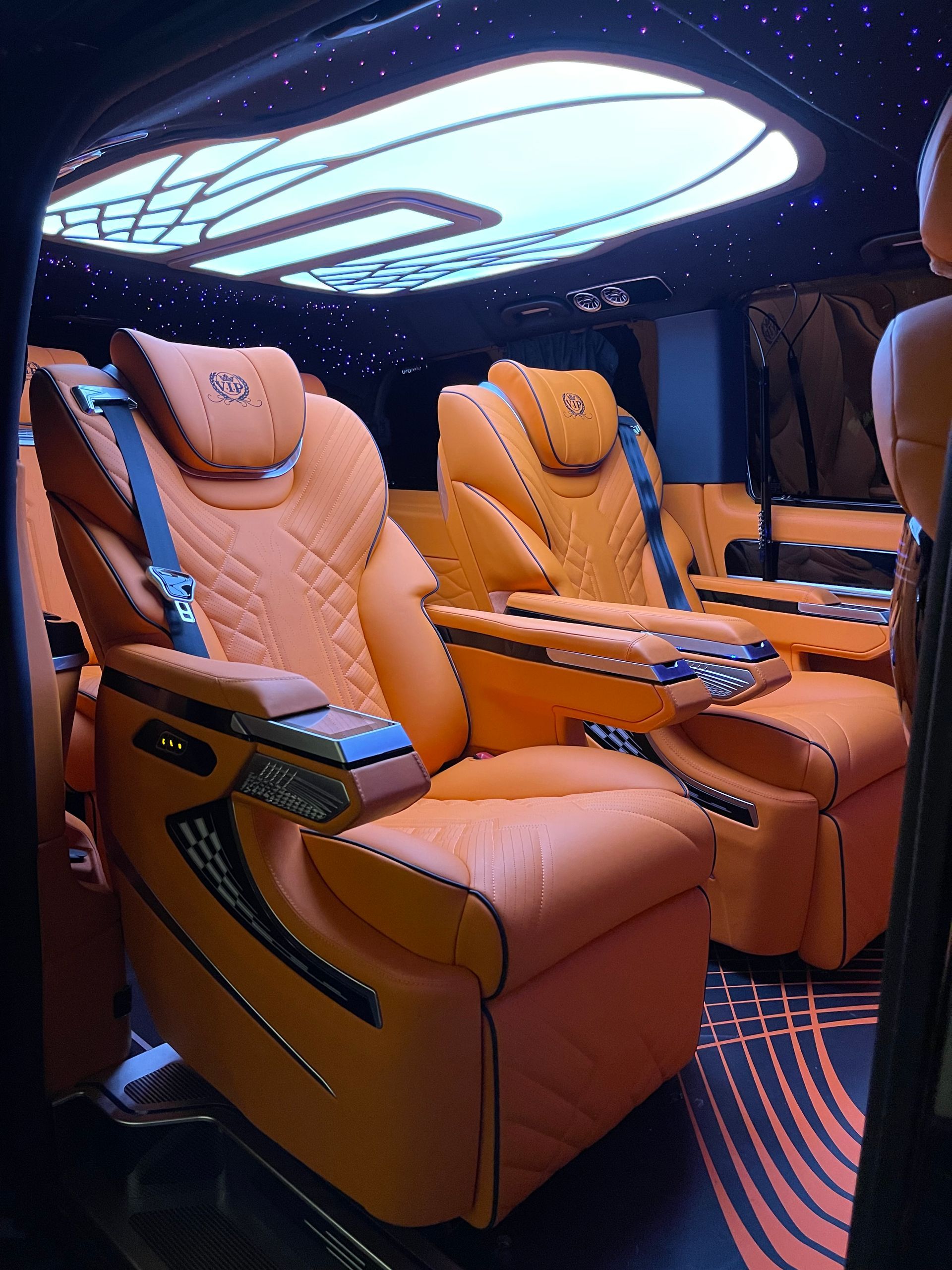 Het interieur van een auto met oranje leren stoelen en een plafondlamp.