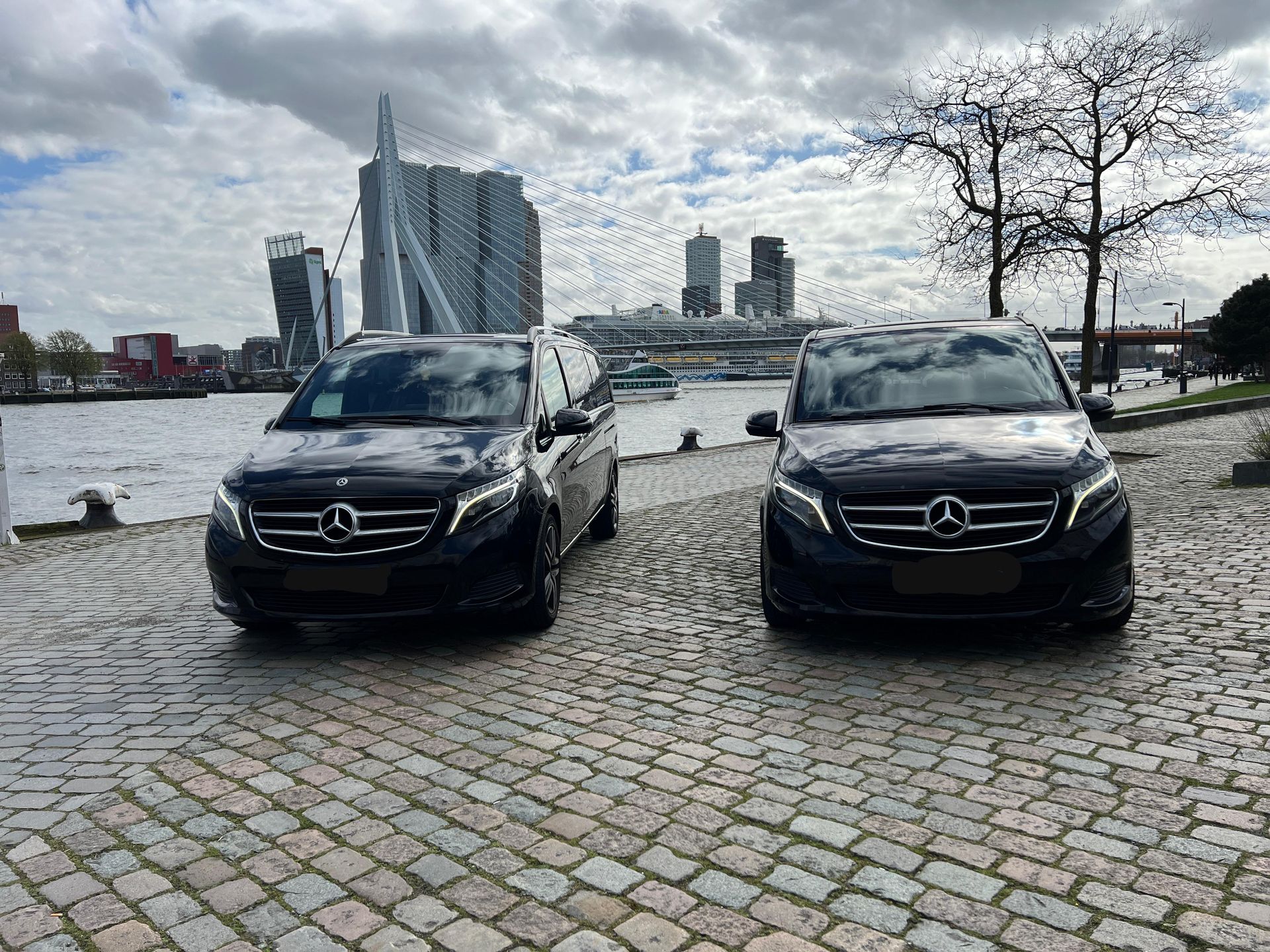 Twee Mercedes-busjes staan ​​naast elkaar geparkeerd op een geplaveide straat.