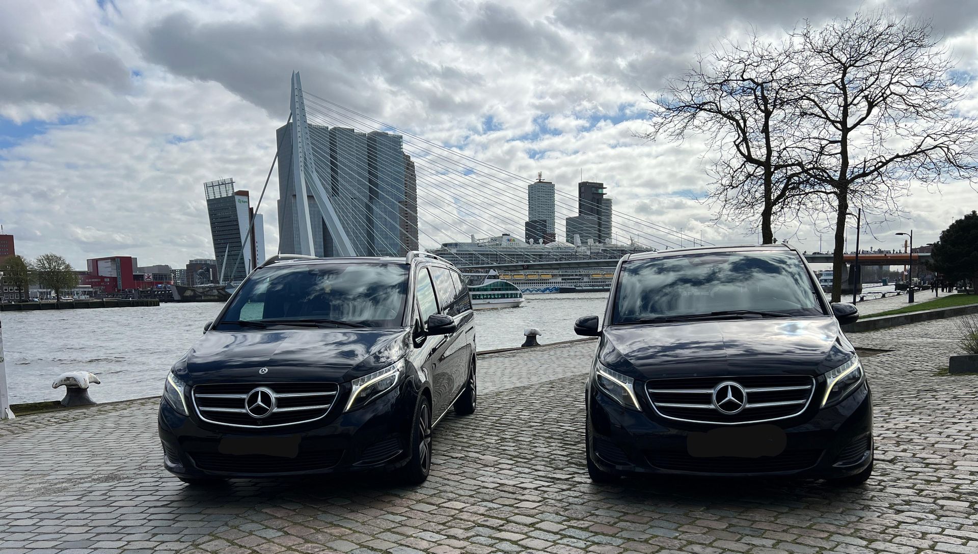 Twee Mercedes-busjes staan ​​naast elkaar geparkeerd op een geplaveide straat. 
mercedes V class