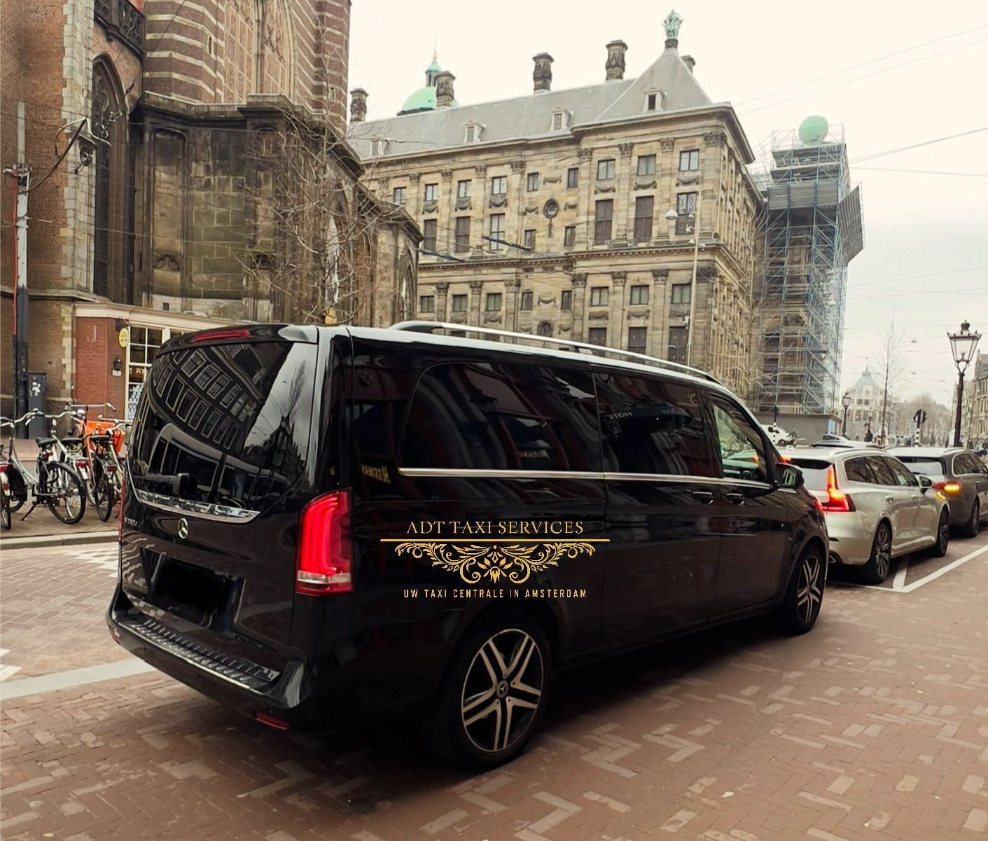 Een zwart busje staat geparkeerd aan de kant van de weg voor een gebouw.