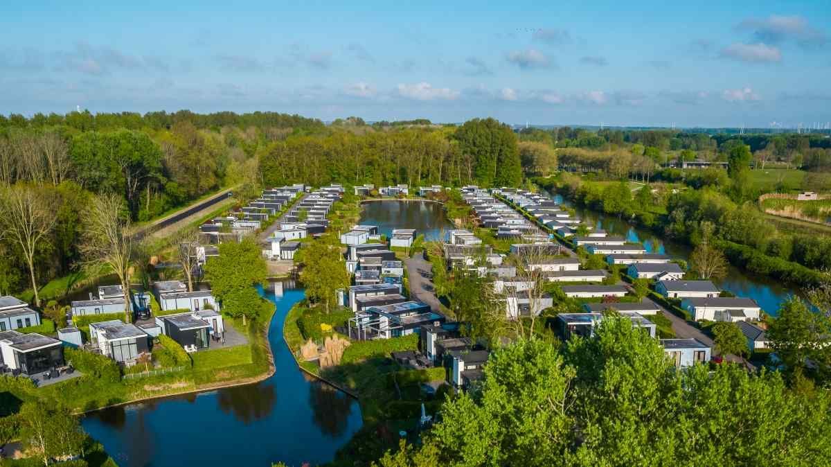 Een luchtfoto van een stacaravanpark omgeven door bomen en water.