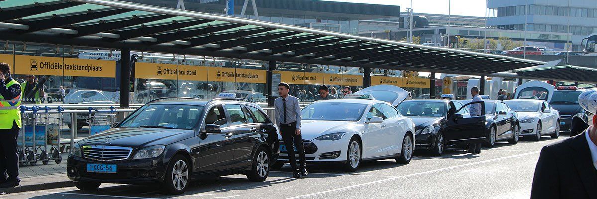 Een rij auto's staat geparkeerd onder een luifel op een vliegveld.