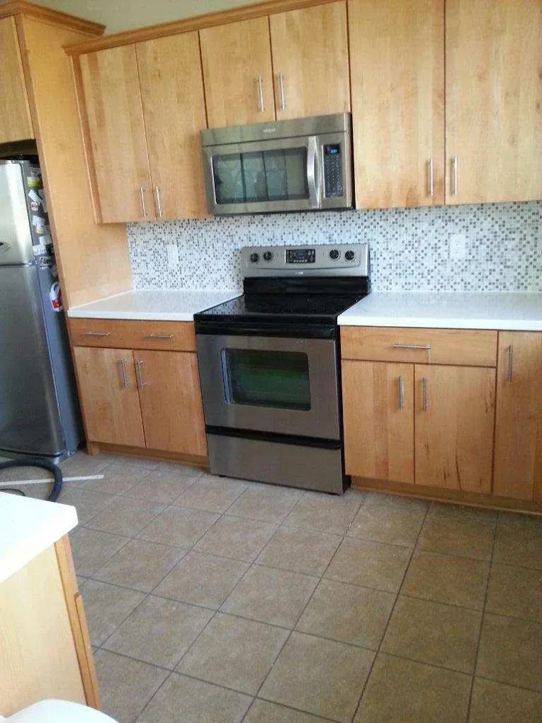 Kitchen with light wood cabinets, stainless steel appliances, and tile backsplash.