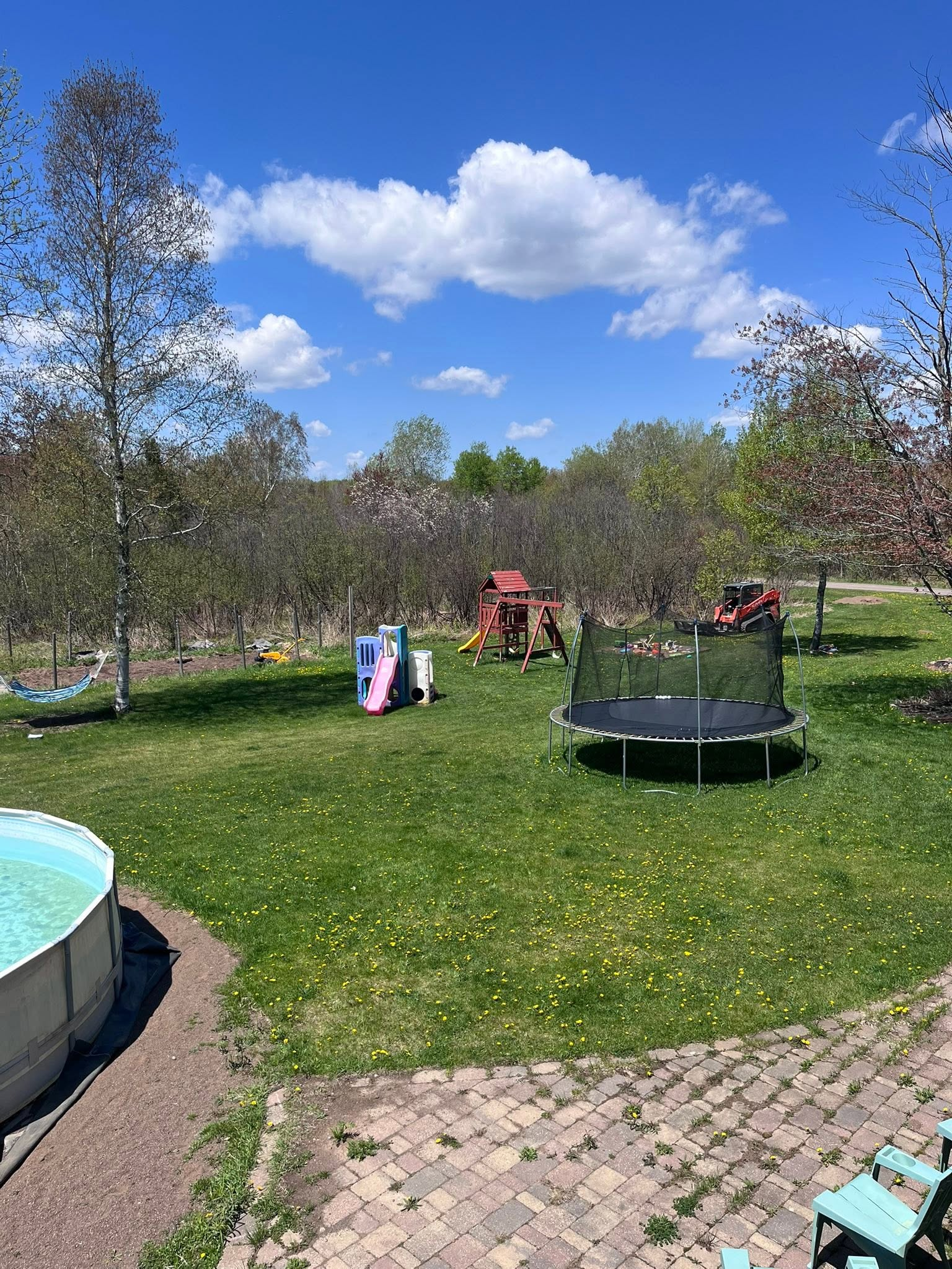 Sunny park playground with children near a pink slide and a round trampoline on green grass