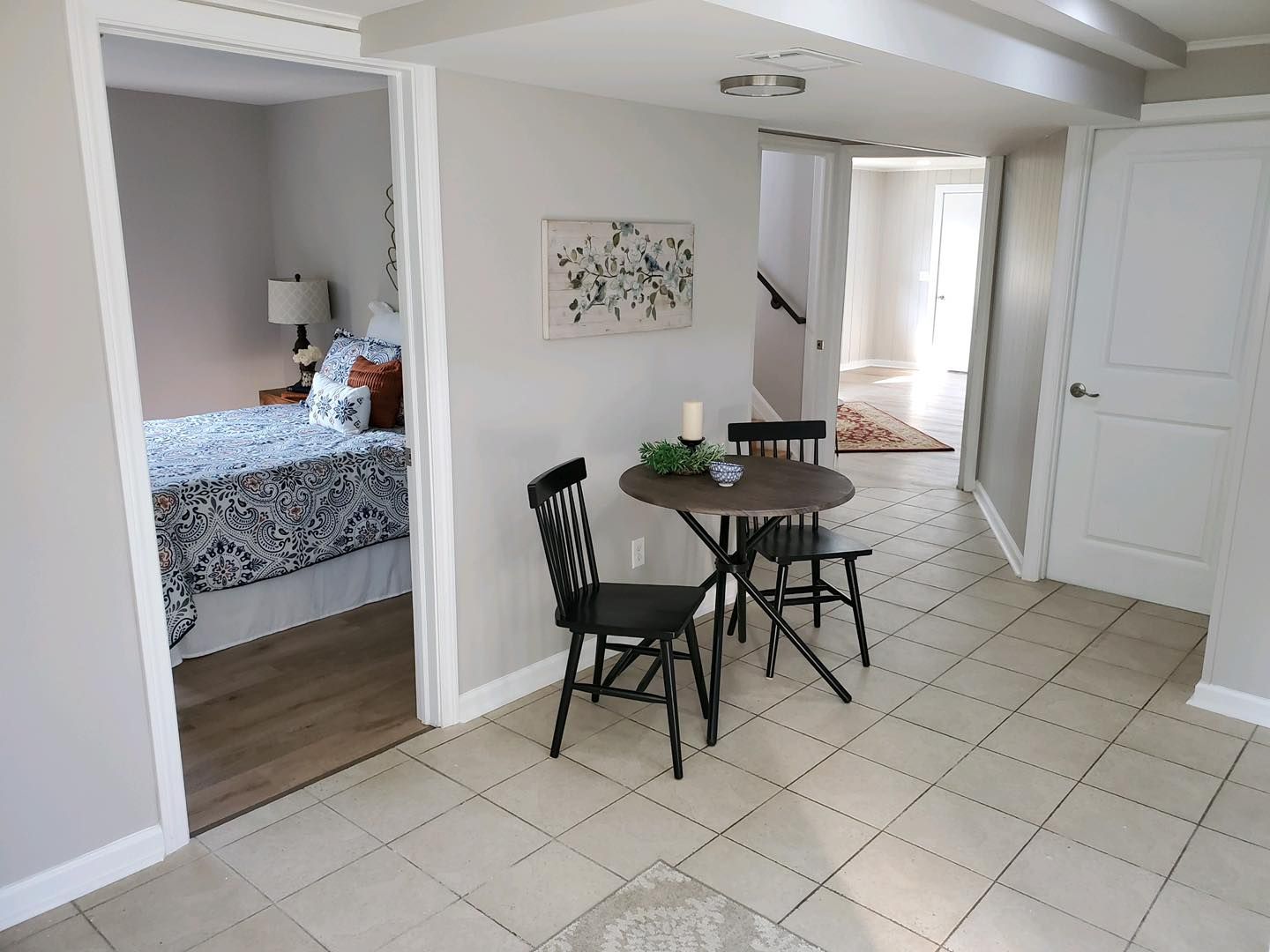 Interior view of a dining area with table and chairs, doorway to bedroom, and hallway to staircase.