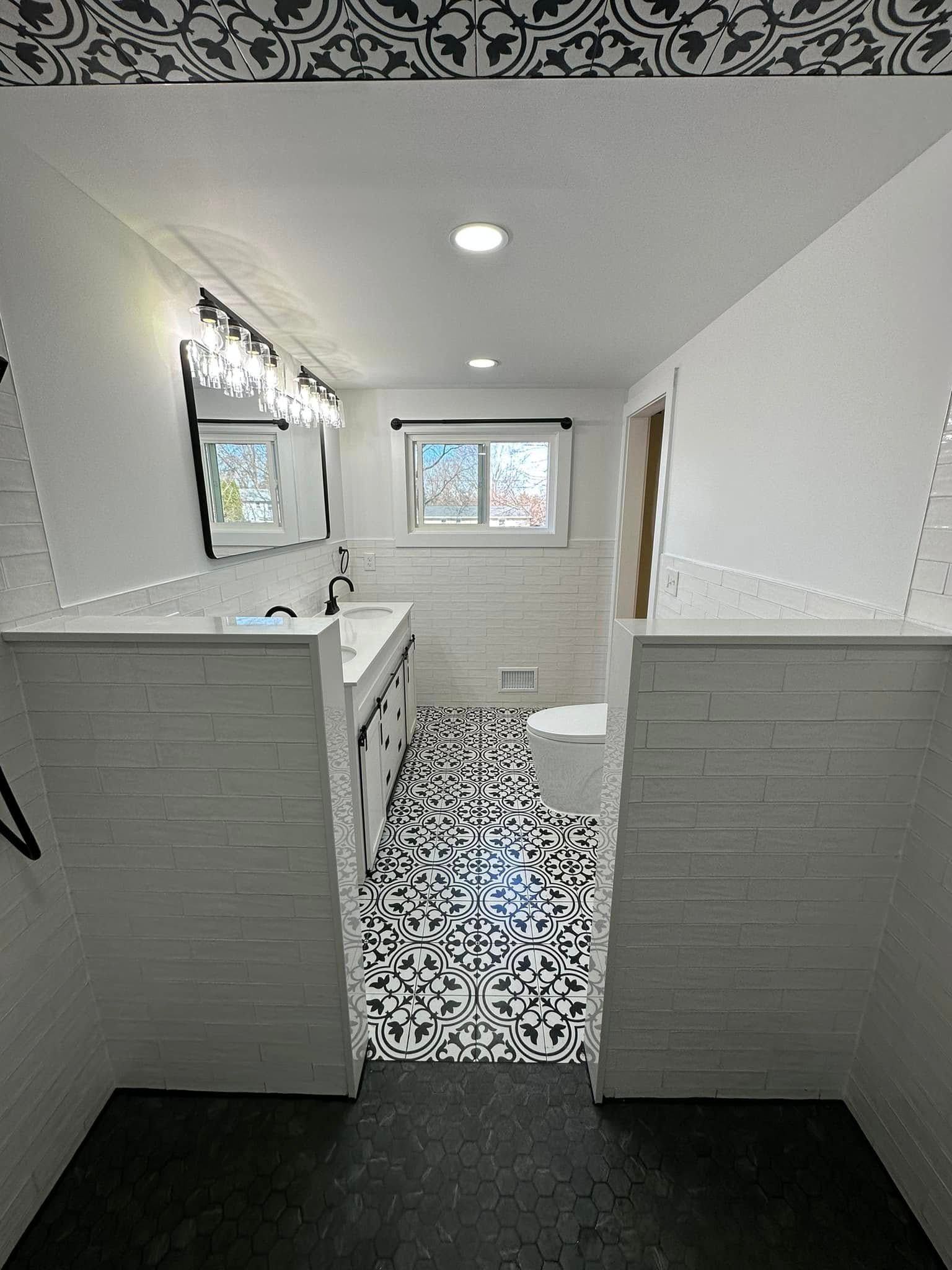 Bathroom with black and white patterned tile floor, white walls, and a large mirror.