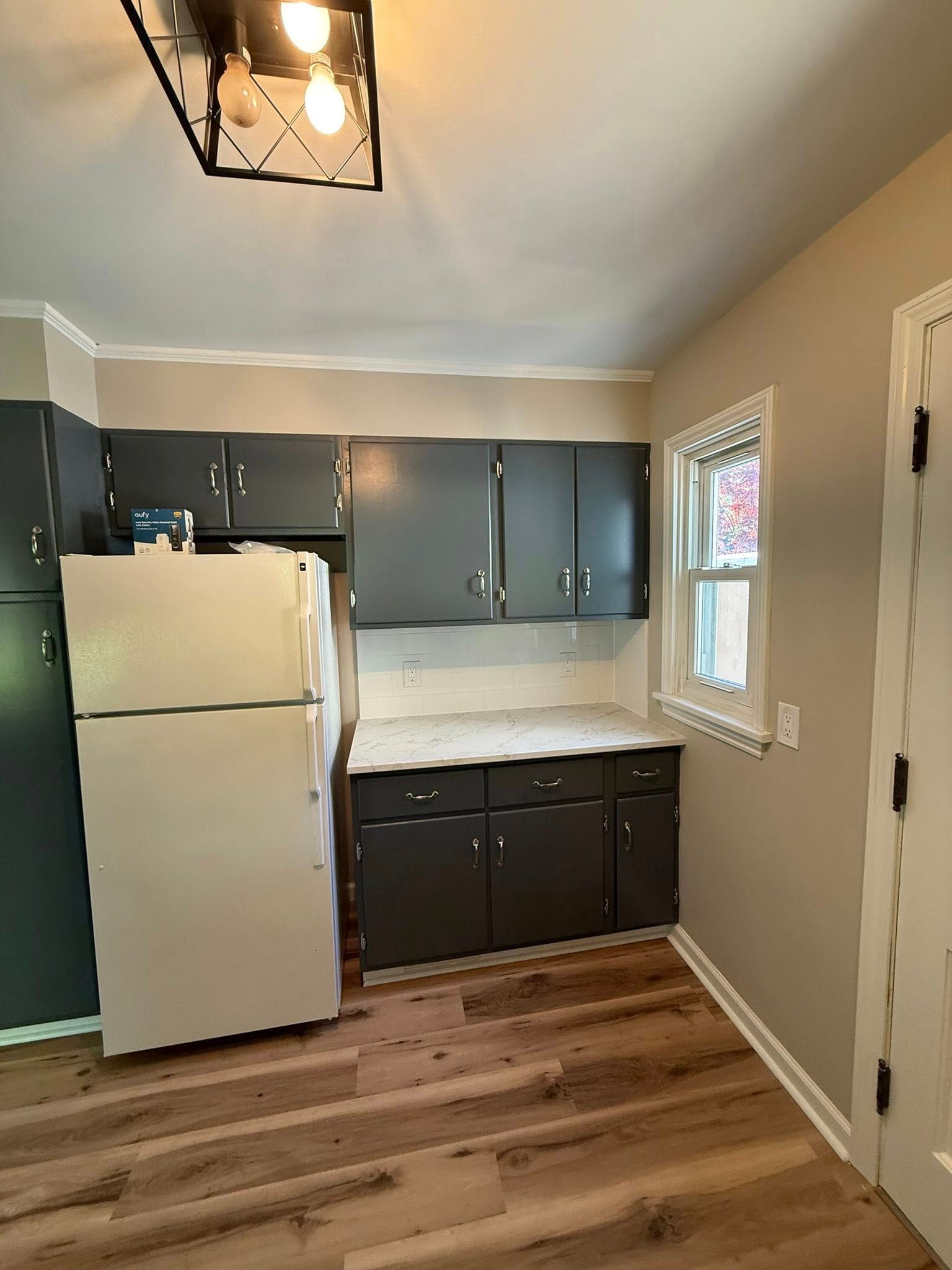 Kitchen with dark gray cabinets, white appliances, and wood-look flooring.