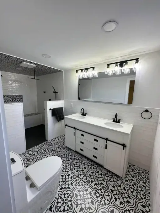 Modern bathroom with black and white patterned tile floor, white vanity, and walk-in shower.