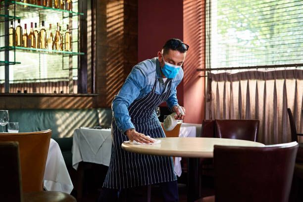 A Man Wearing a Mask Is Cleaning a Table in A Restaurant - Parma, OH - Family First Car Care