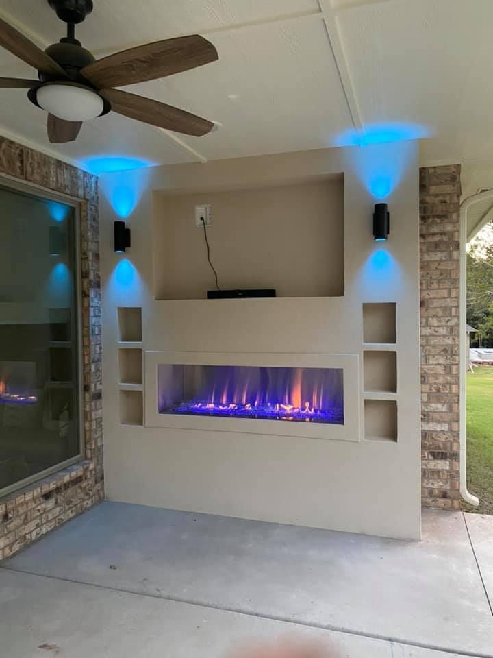 Outdoor entertainment area with fireplace, blue LED lighting, and built-in shelving. Outdoor entertainment area with fireplace, blue LED lighting, and built-in shelving.