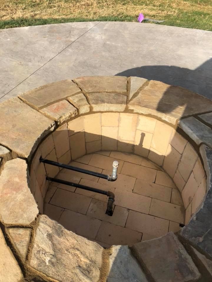 Circular stone fire pit with gas pipes, built into a concrete patio. Circular stone fire pit with gas pipes, built into a concrete patio.