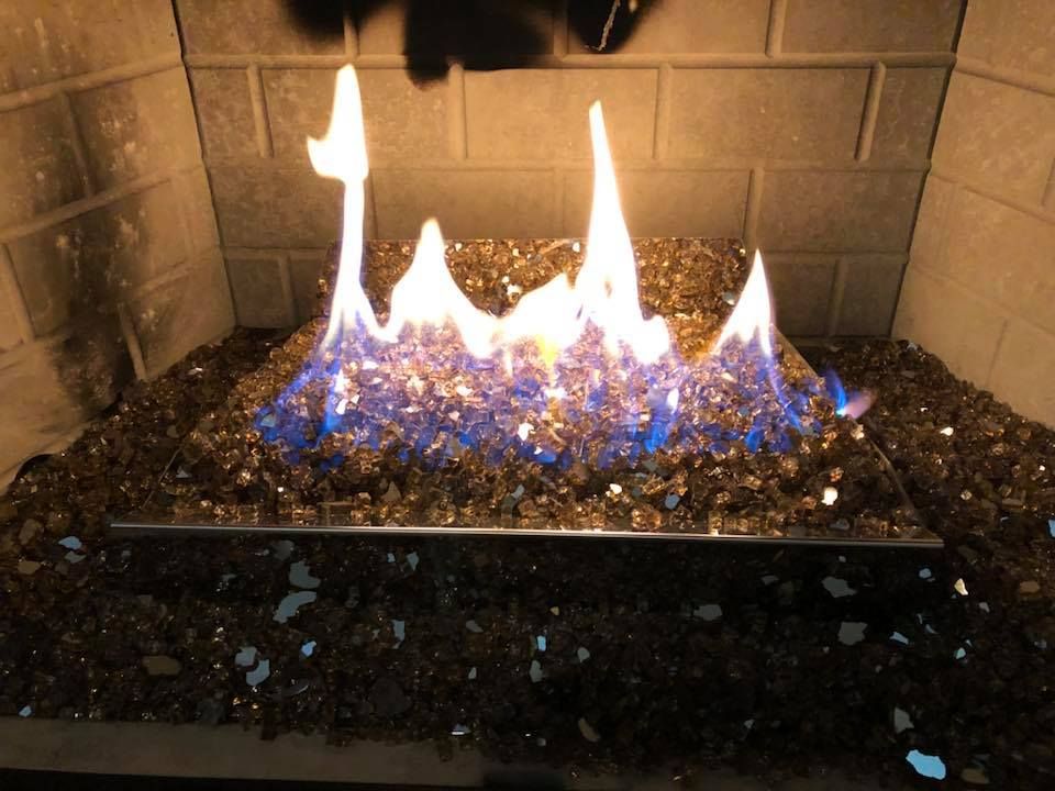 Fireplace with flames rising from blue and gold glass rocks within a brick hearth. Fireplace with flames rising from blue and gold glass rocks within a brick hearth.