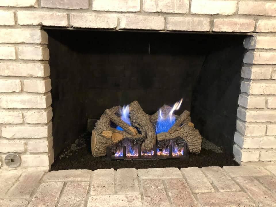Fireplace with brick surround, gas logs with blue flames. Fireplace with brick surround, gas logs with blue flames.