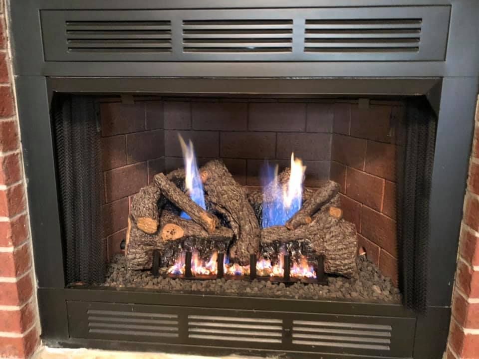 Gas fireplace with burning logs and blue flames. Gas fireplace with burning logs and blue flames.