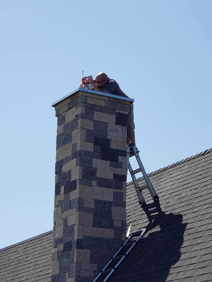 Person on a ladder repairing chimney; clear blue sky. Person on a ladder repairing chimney; clear blue sky.