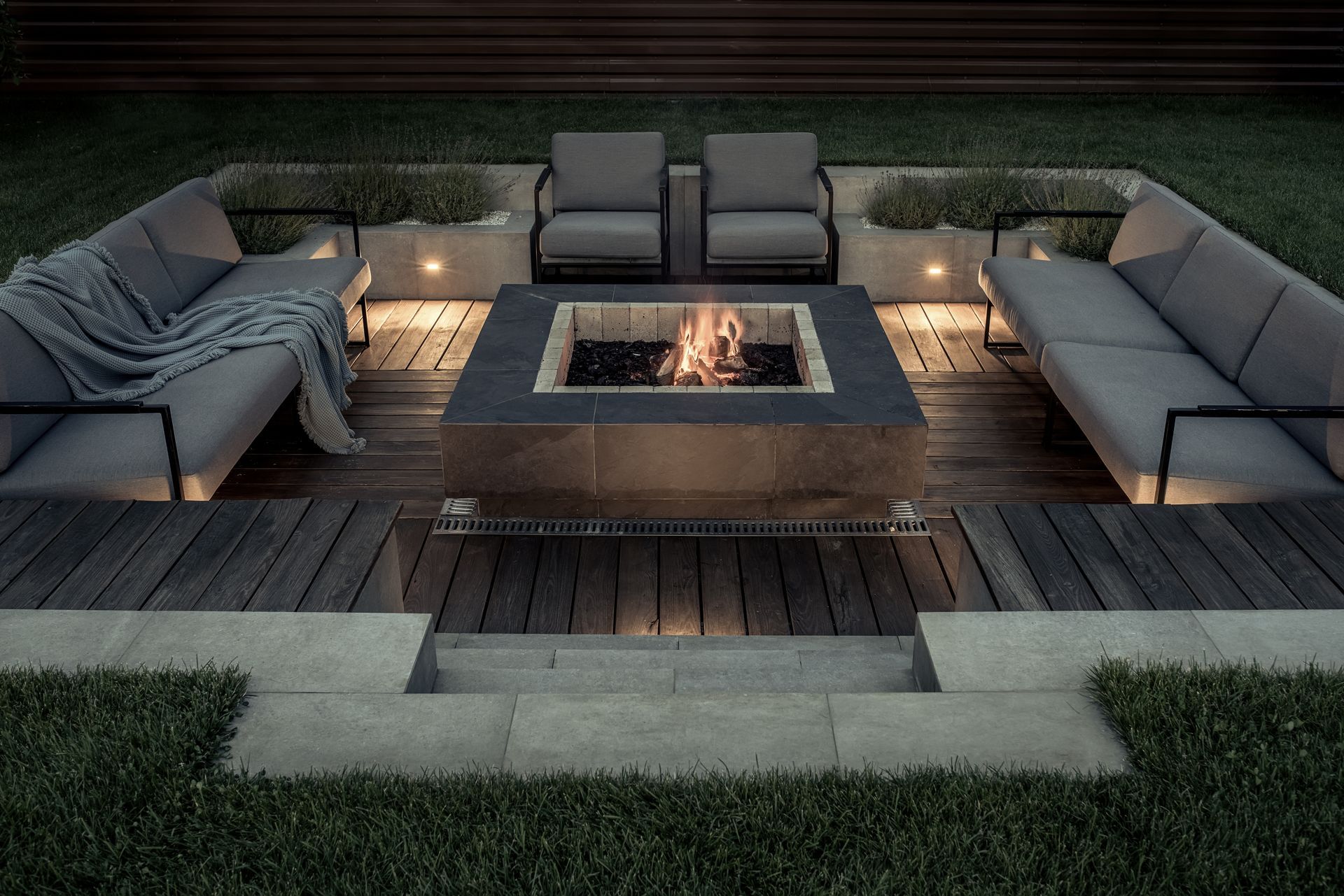 A burning fire pit and outdoor couches in a backyard
.