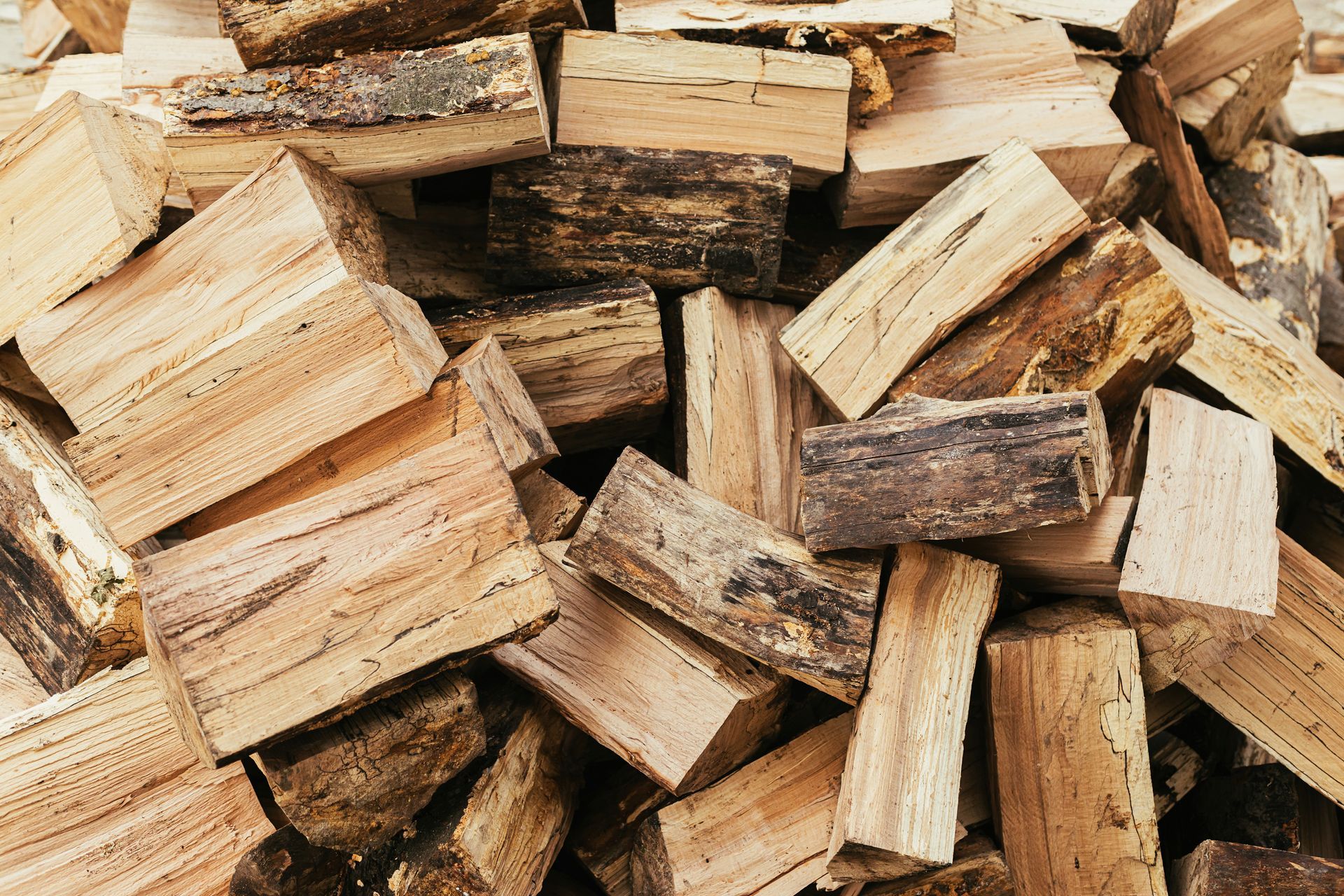 Stack of split firewood logs piled closely together, showing rough bark. Stack of split firewood logs piled closely together, showing rough bark.